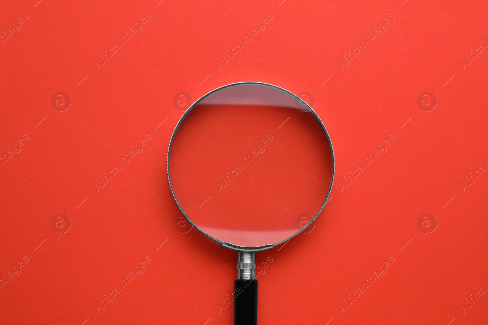 Photo of Magnifying glass on red background, top view