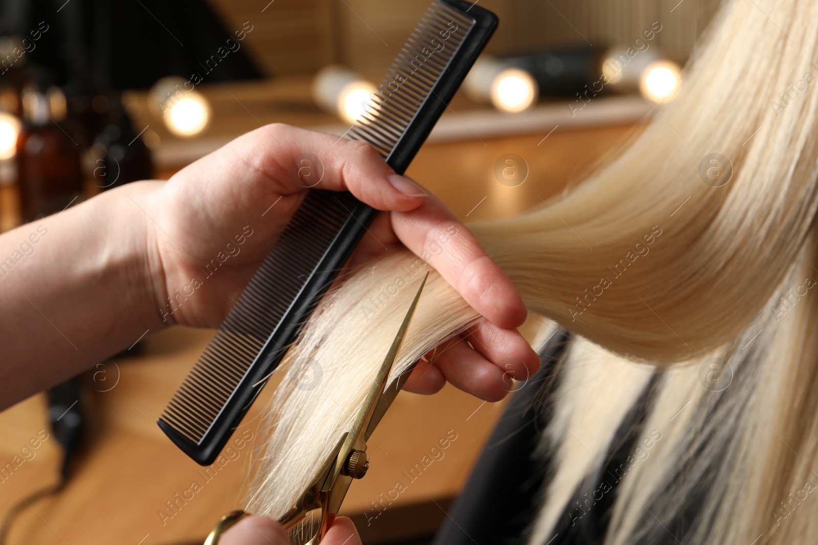 Photo of Hairdresser cutting client's hair with scissors in salon, closeup