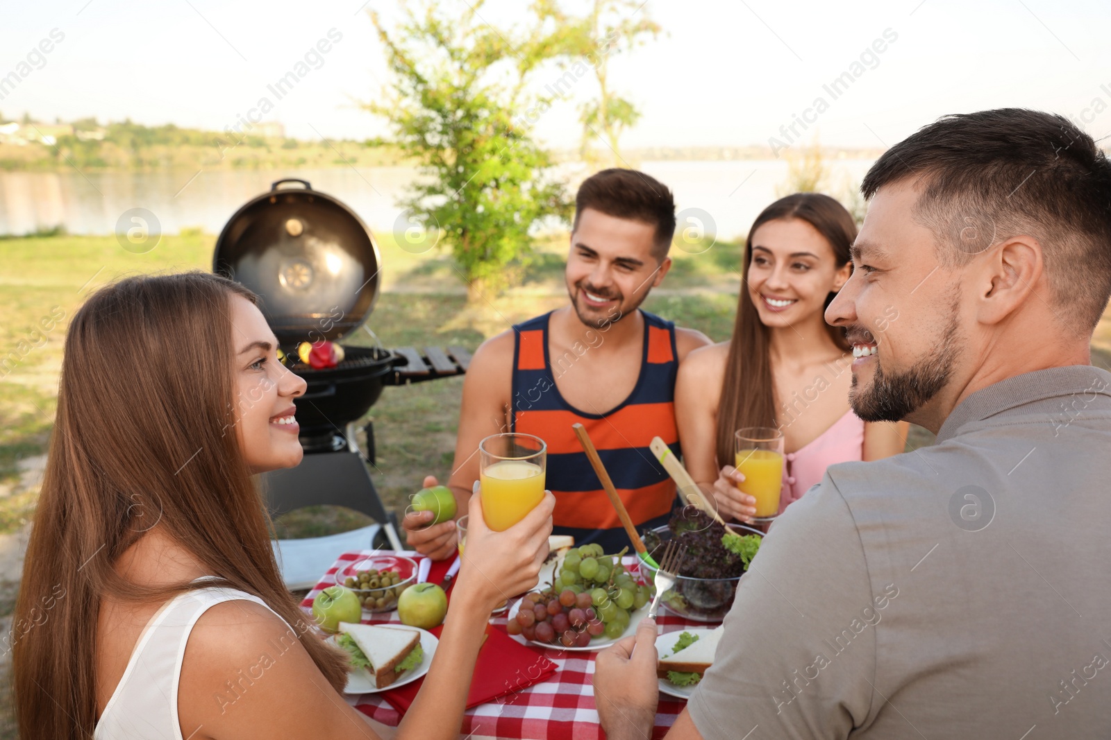 Photo of Happy young people having picnic at table in park