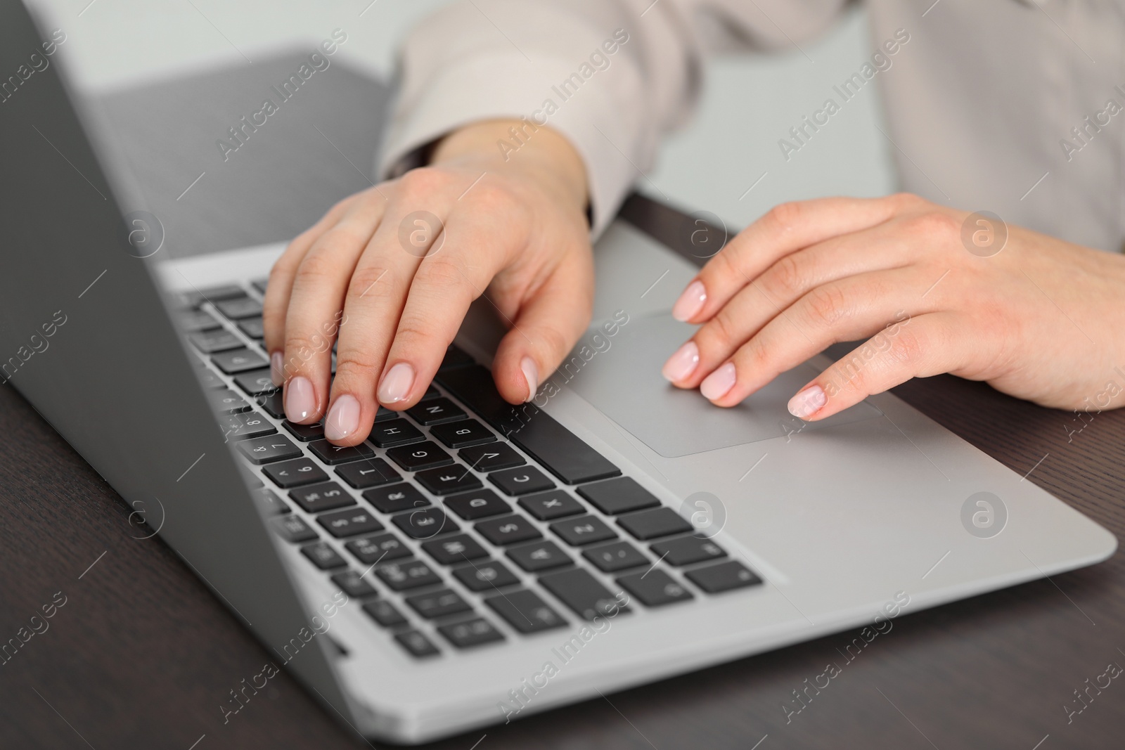 Photo of Woman working on laptop at table, closeup. Electronic document management