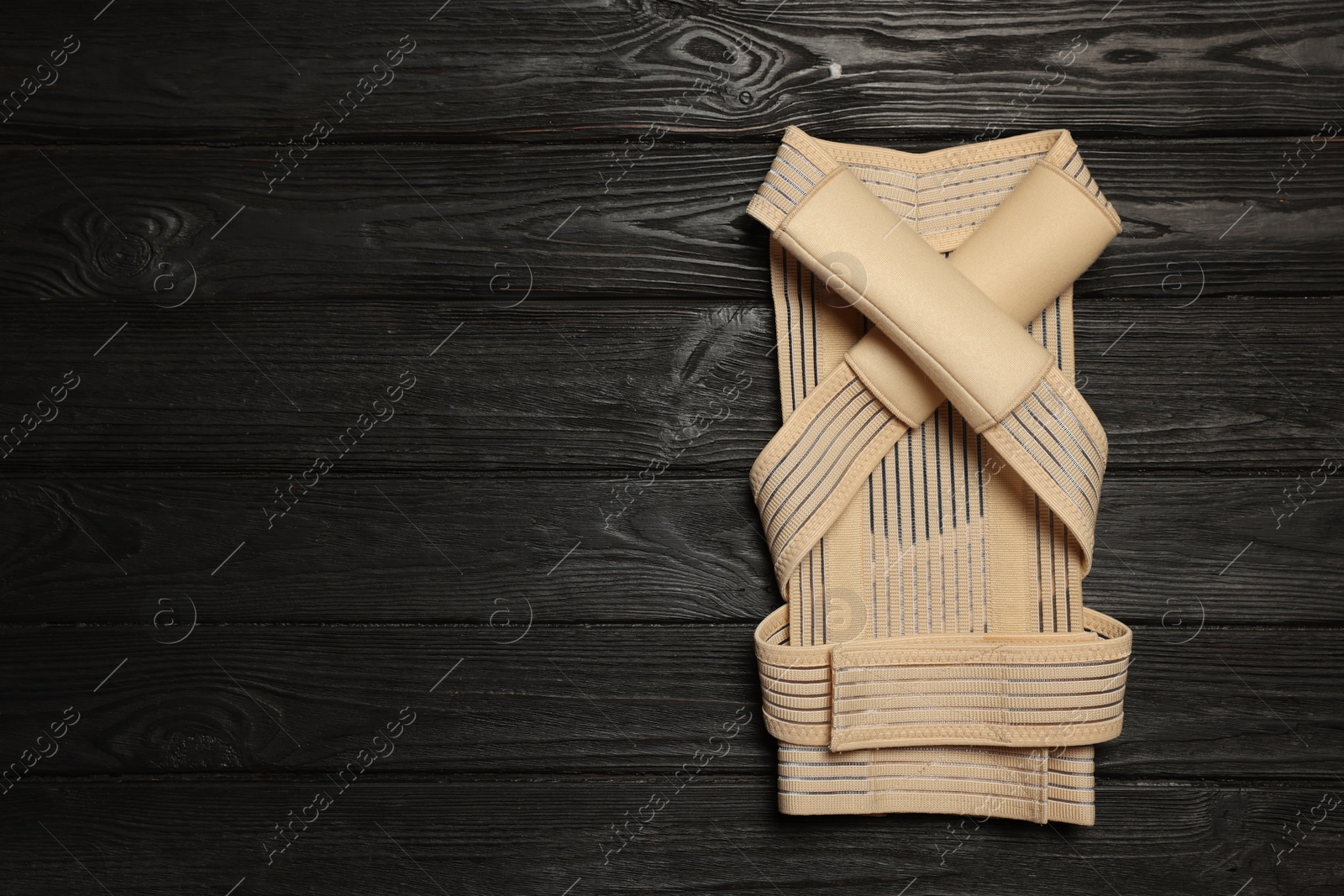 Photo of Beige posture corrector on black wooden table, top view. Space for text