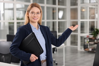 Photo of Happy real estate agent with leather portfolio indoors