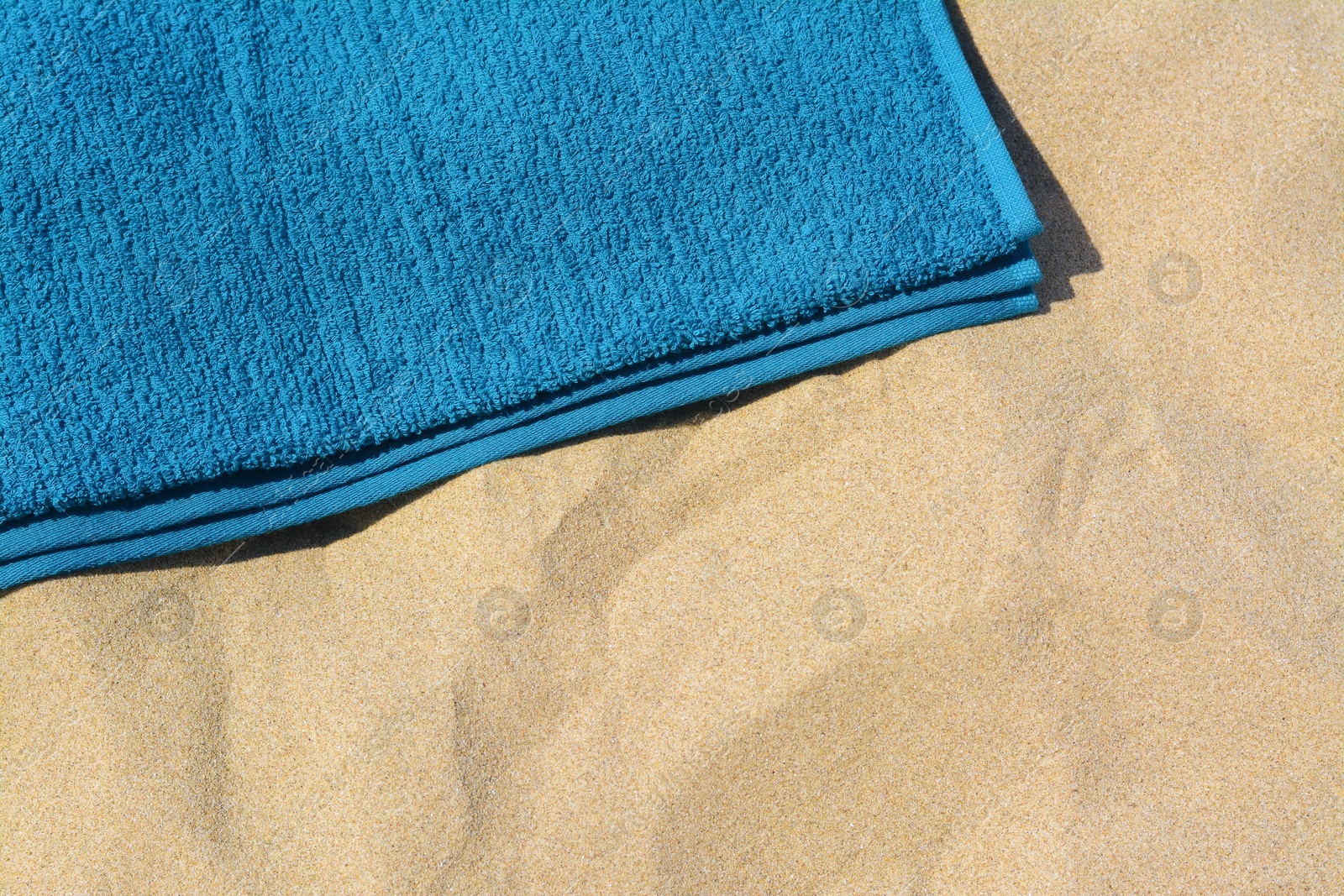 Photo of Soft blue beach towel on sand, above view. Space for text