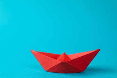 Photo of Handmade red paper boat on light blue background.  Origami art