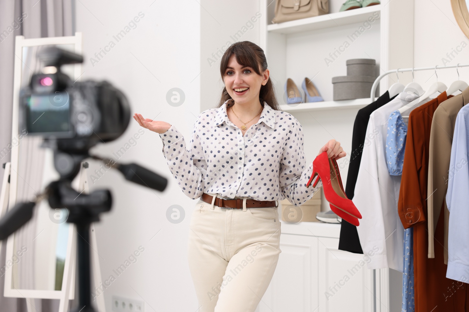 Photo of Smiling fashion blogger showing her shoes while recording video at home