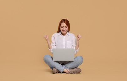 Photo of Happy young woman with laptop on beige background