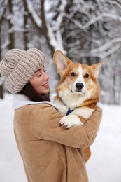 Woman with adorable Pembroke Welsh Corgi dog in snowy park