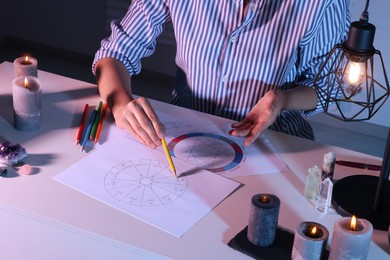 Photo of Astrologer predicting future with zodiac wheel at table indoors, closeup