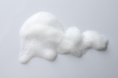 Photo of Drop of fluffy soap foam on white background, top view