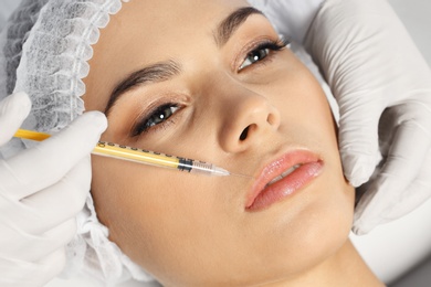 Young woman getting lips injection in clinic, closeup. Cosmetic surgery