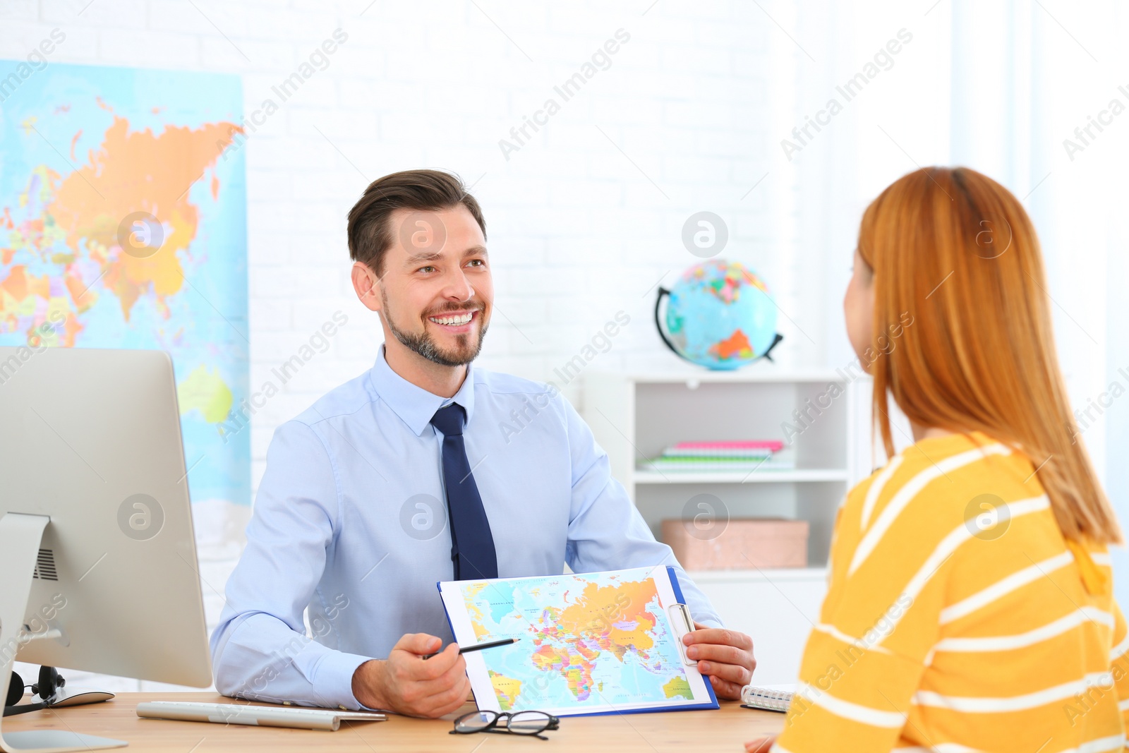 Photo of Male manager consulting client in travel agency