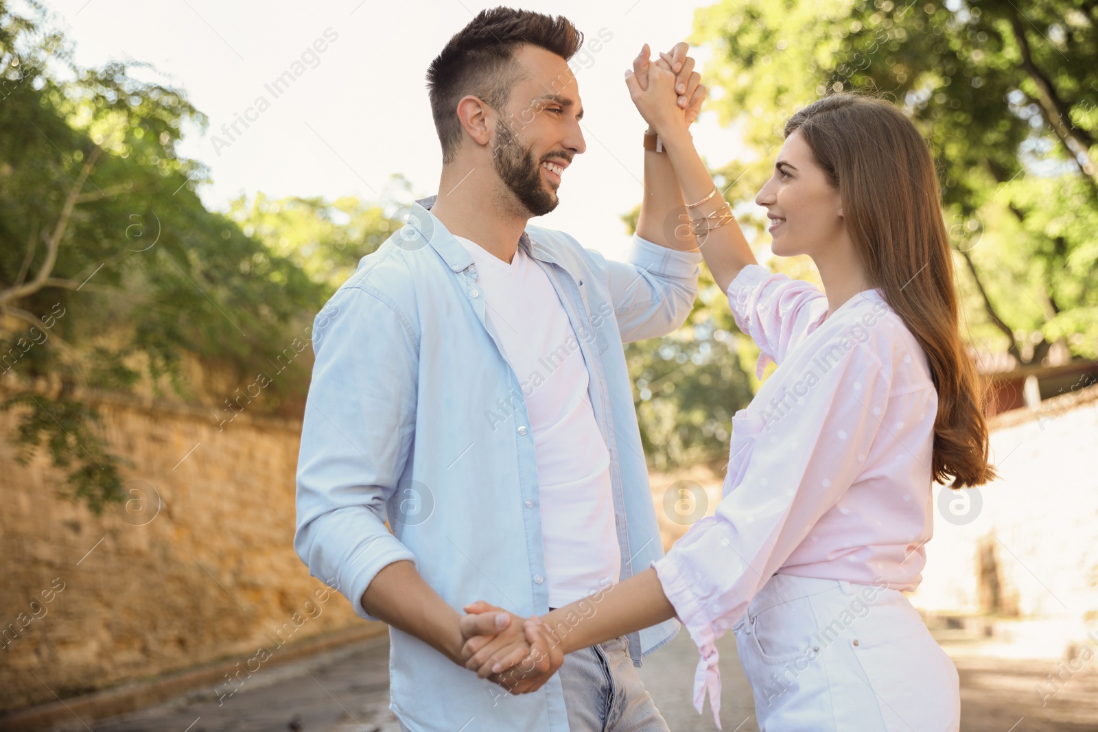 Photo of Lovely young couple dancing together outdoors on sunny day