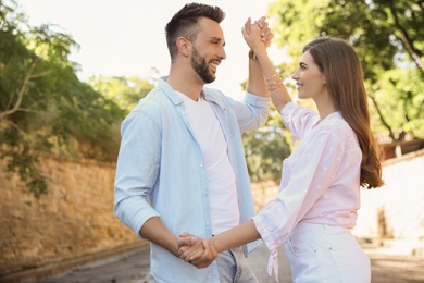 Photo of Lovely young couple dancing together outdoors on sunny day