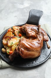 Photo of Tasty cooked rabbit meat with vegetables on light grey table