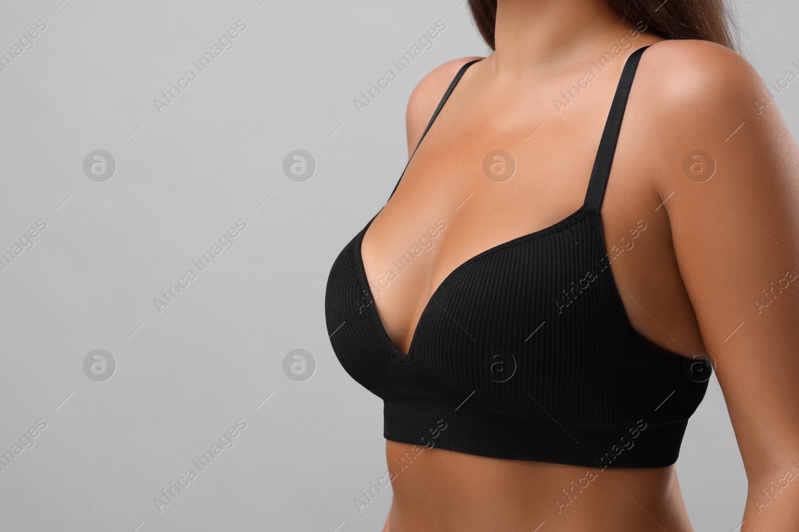 Photo of Woman with beautiful breast on light grey background, closeup. Space for text
