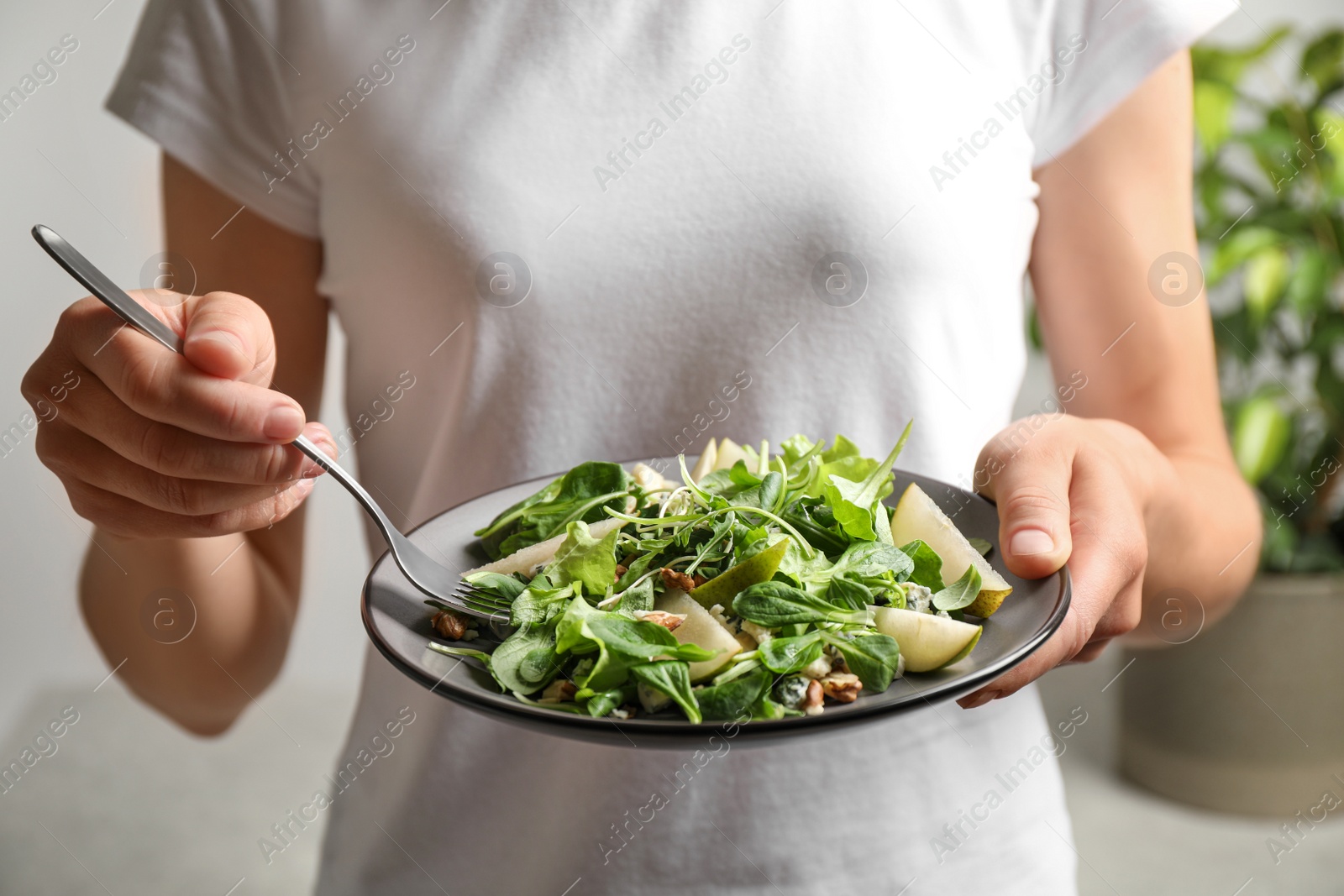 Photo of Woman with tasty pear salad on blurred background, closeup