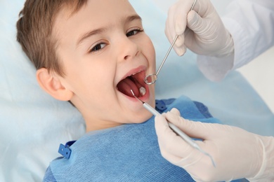 Photo of Dentist examining cute boy's teeth in modern clinic