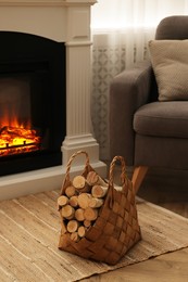 Wicker basket with wood near fireplace in room