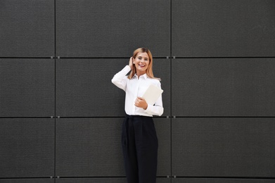 Photo of Female real estate agent with tablet near dark wall