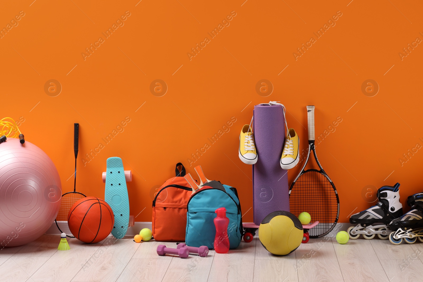 Photo of Many different sports equipment near orange wall indoors