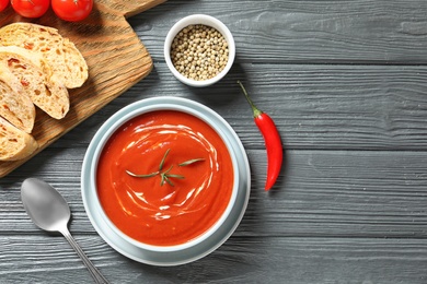 Photo of Fresh homemade tomato soup served with bread on wooden table, top view. Space for text