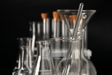 Photo of Different laboratory glassware on black background, closeup