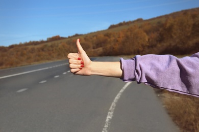 Photo of Woman hitchhiking on mountain road, focus on hand