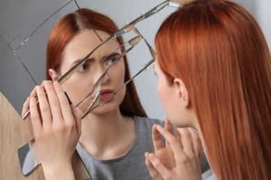 Photo of Sad young woman suffering from mental problems near broken mirror