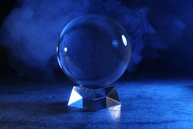 Photo of Magic crystal ball on table against dark background. Making predictions