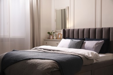 Photo of Comfortable bed with pillows and bedding in stylish room. Interior design