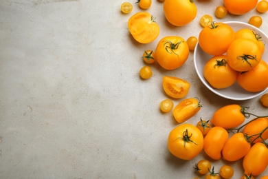 Photo of Ripe yellow tomatoes on grey table, flat lay. Space for text