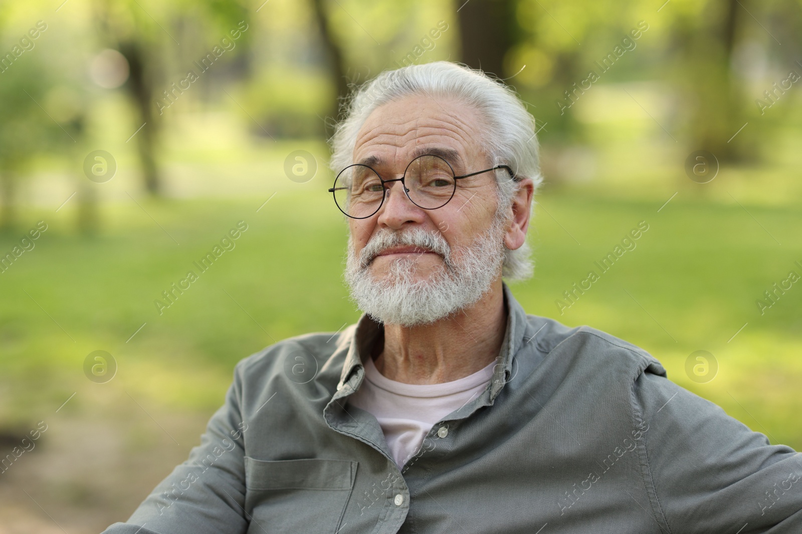 Photo of Portrait of happy grandpa with glasses in park