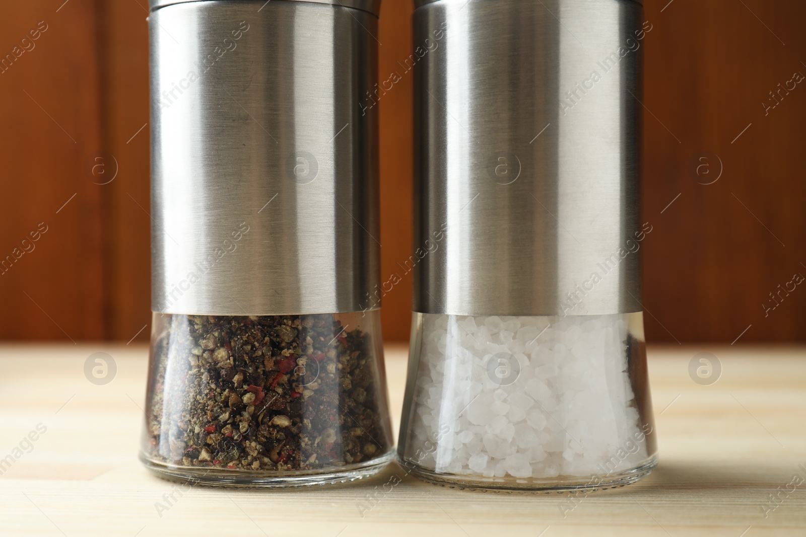 Photo of Salt and pepper shakers on light wooden table, closeup