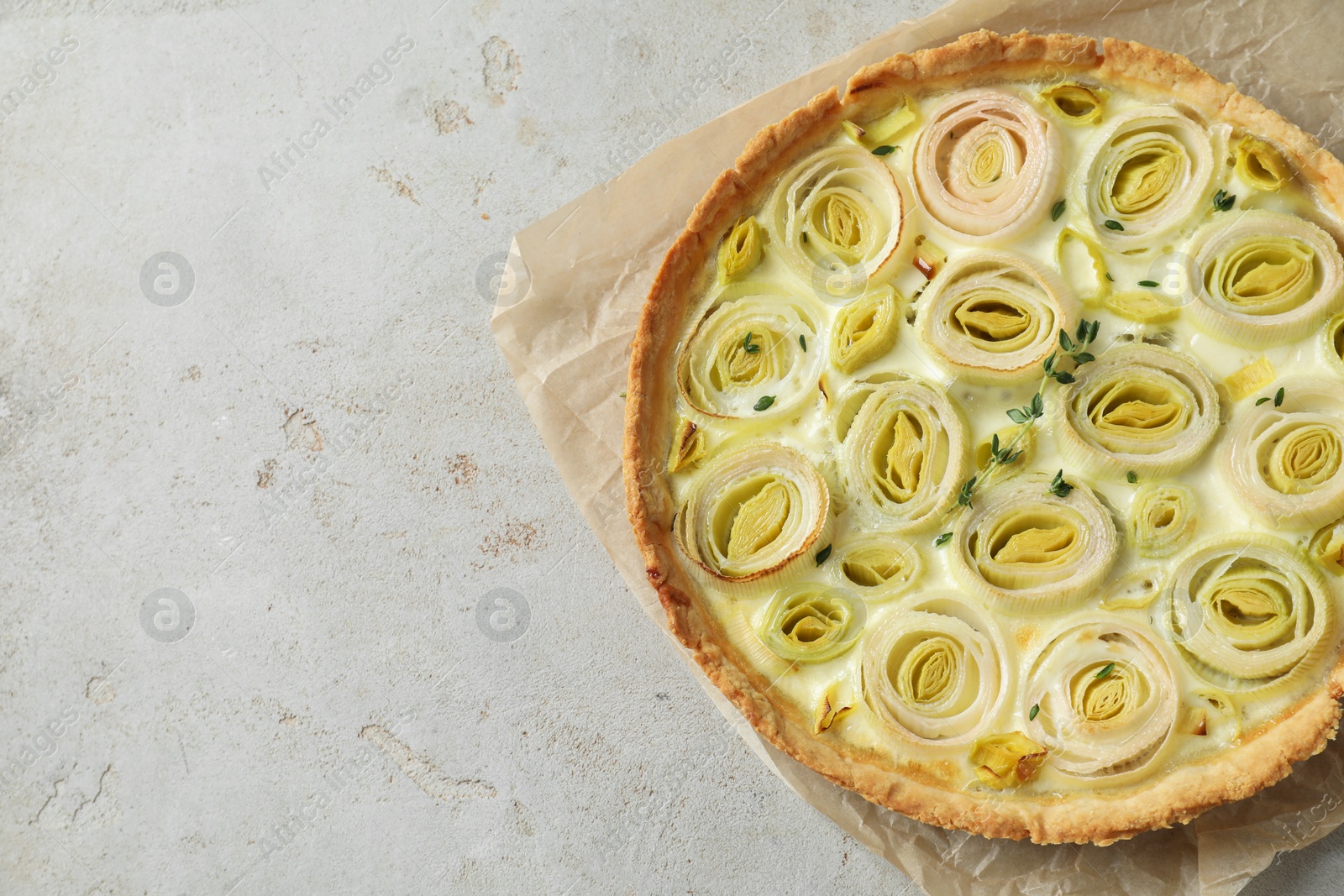 Photo of Tasty leek pie on grey textured table, top view. Space for text