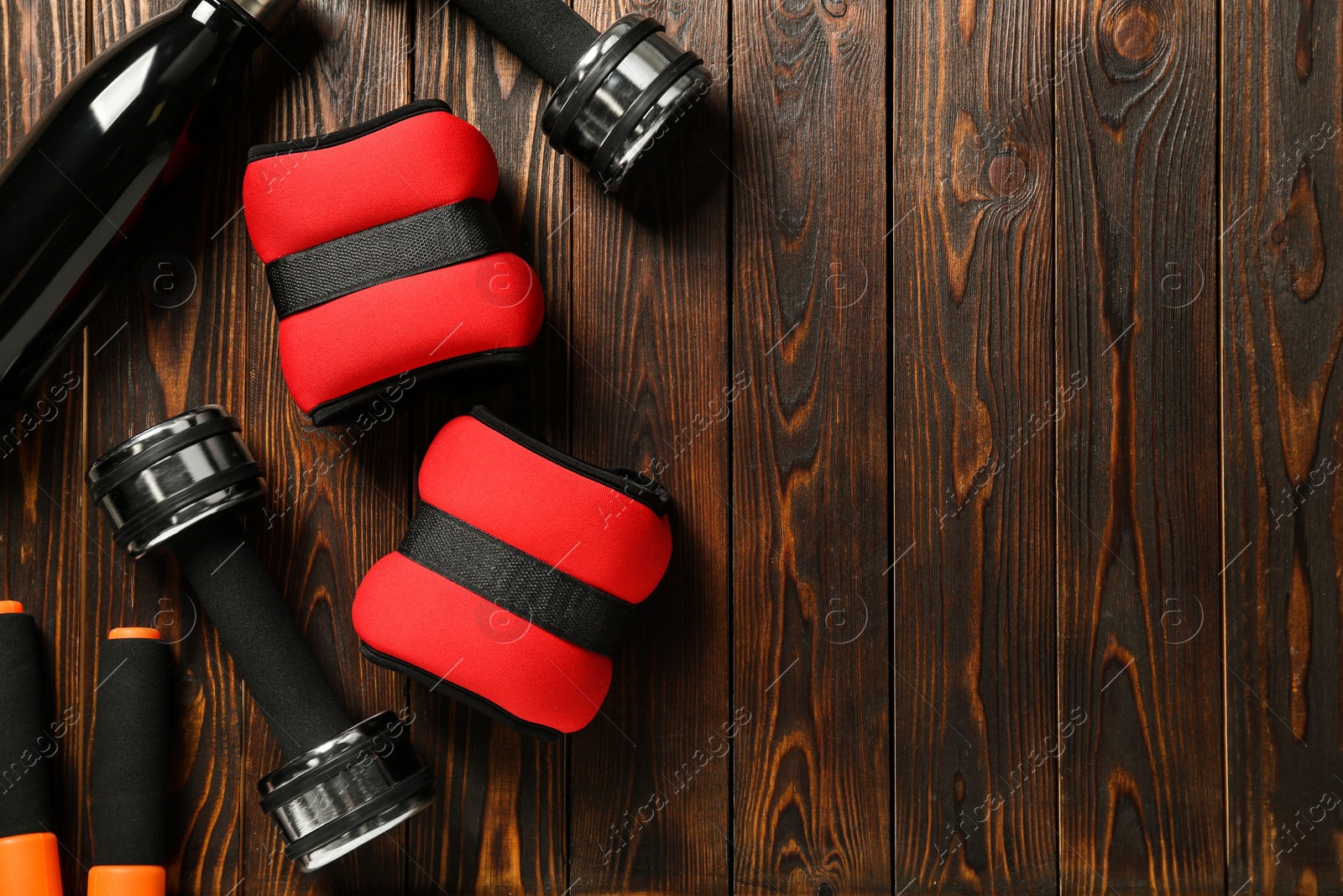 Photo of Red weighting agents and sport equipment on wooden table, flat lay. Space for text