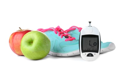 Photo of Digital glucometer, apples and sneakers on white background. Diabetes concept