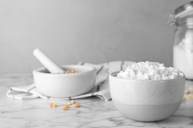 Bowl with corn starch on marble table. Space for text