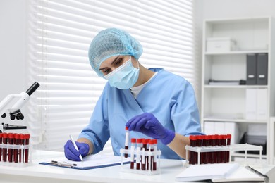 Photo of Laboratory testing. Doctor with blood samples in tubes at white table indoors