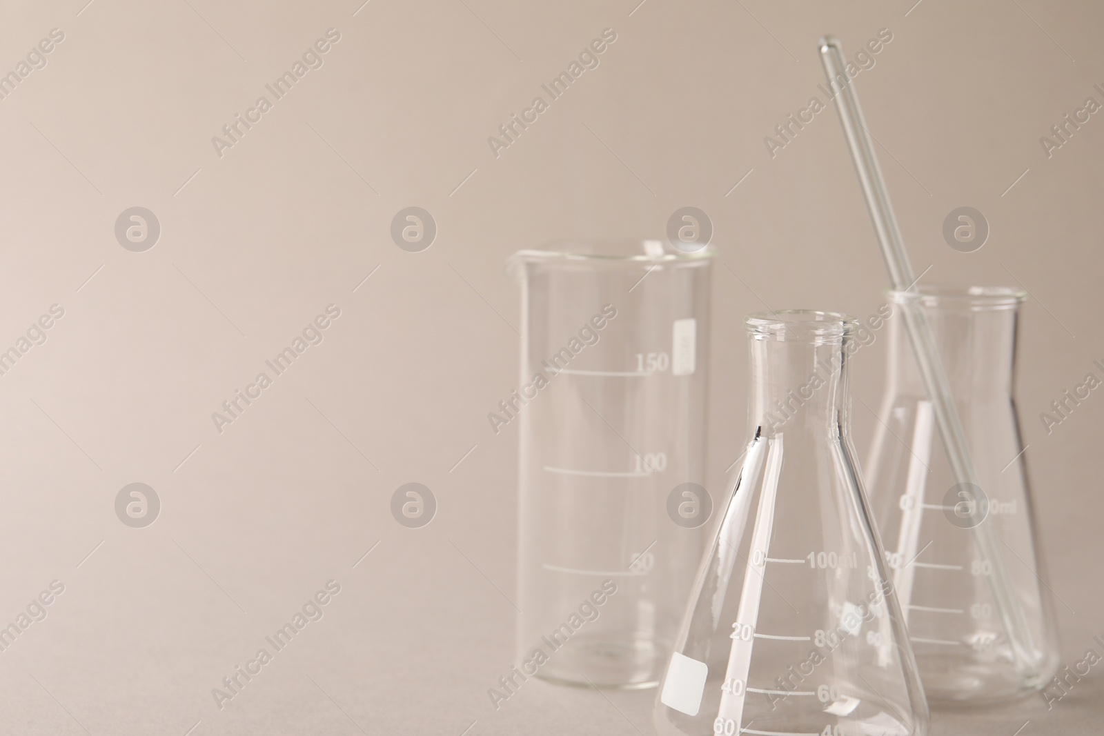Photo of Different laboratory glassware on beige background, space for text