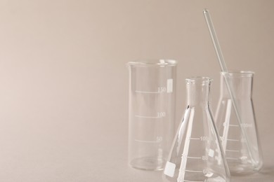 Different laboratory glassware on beige background, space for text