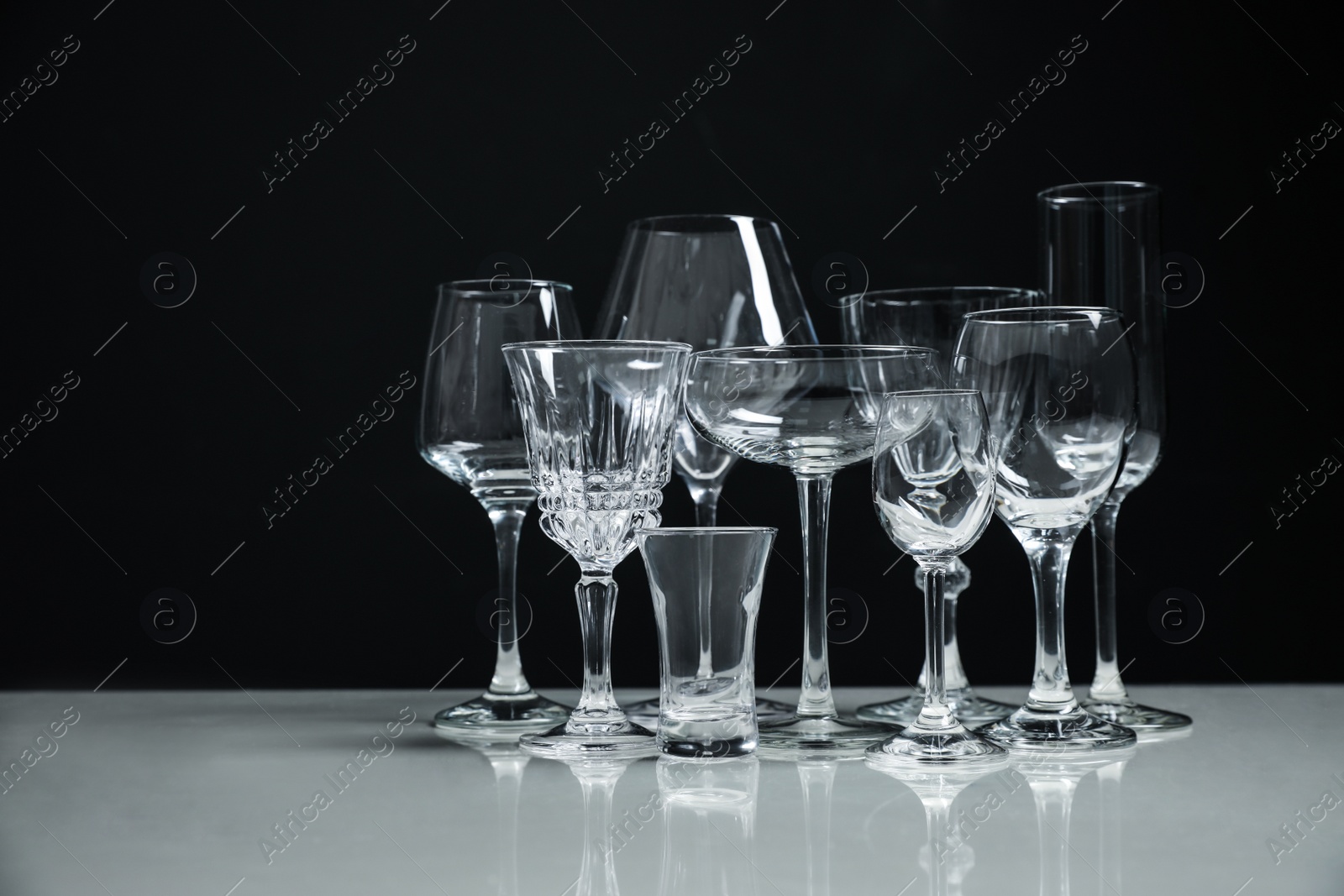 Photo of Set of bar glassware on white table against black background