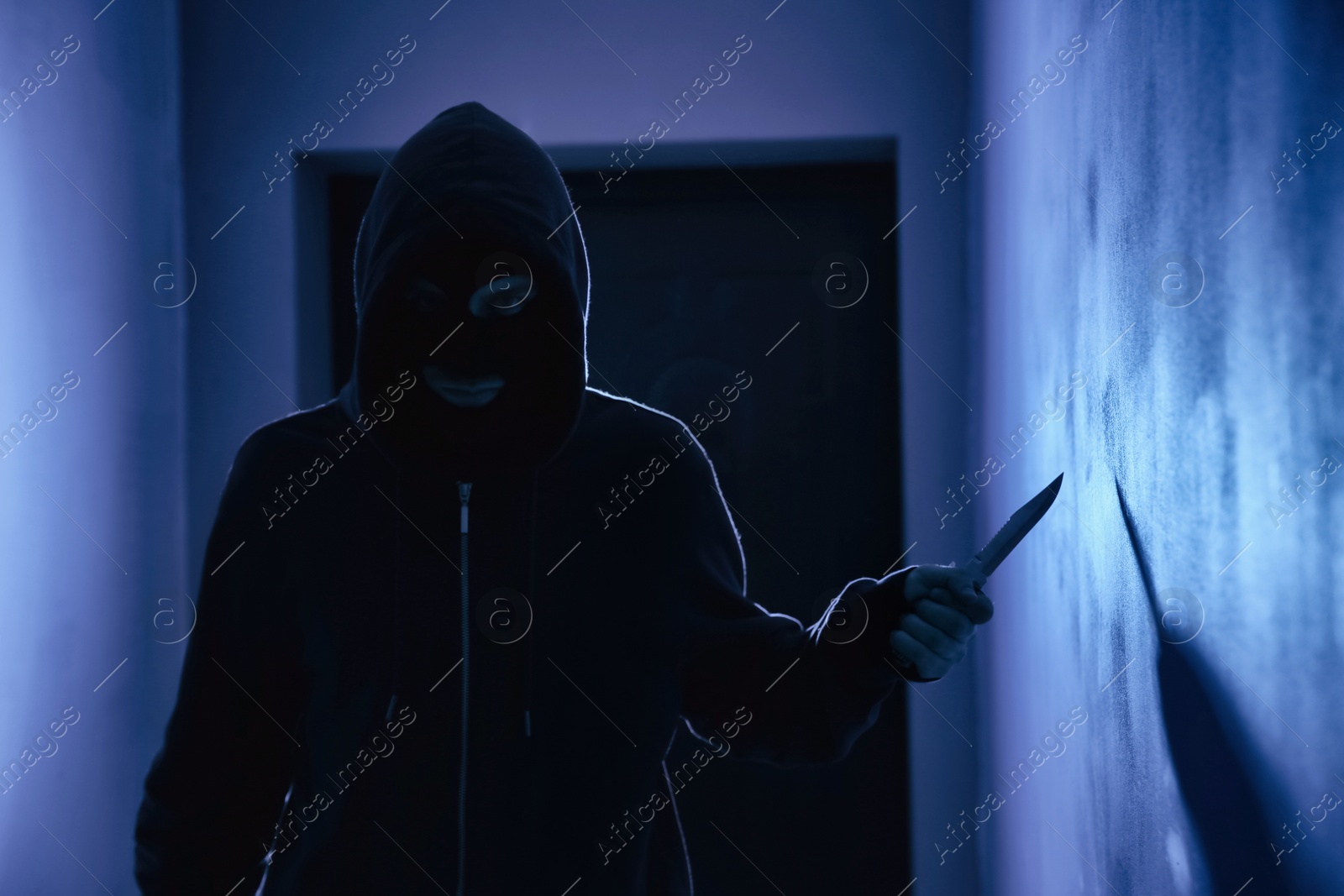 Photo of Man with knife in dark room. Dangerous criminal