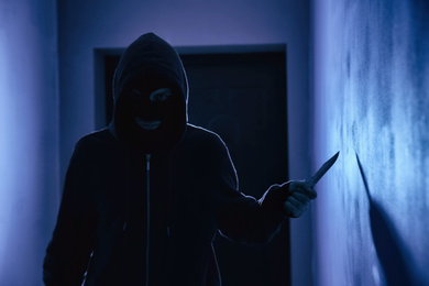 Man with knife in dark room. Dangerous criminal