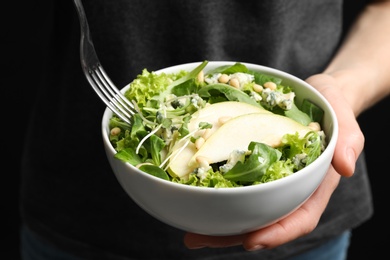 Photo of Woman eating fresh salad with pear, closeup