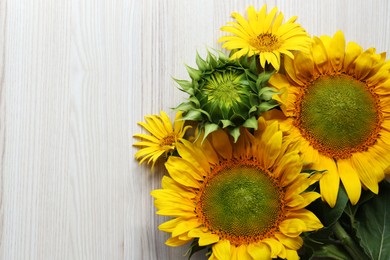 Photo of Beautiful sunflowers on wooden table, flat lay. Space for text