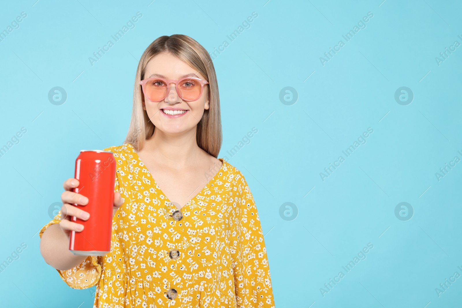 Photo of Beautiful happy woman holding red beverage can on light blue background. Space for text