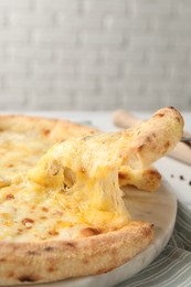 Photo of Taking piece of delicious cheese pizza at table, closeup