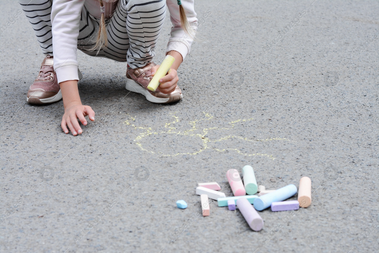 Photo of Little child drawing sun with chalk on asphalt, closeup