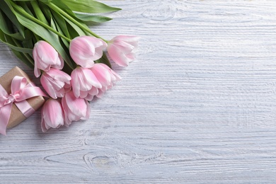 Photo of Beautiful tulips and gift box for Mother's Day on wooden background, top view