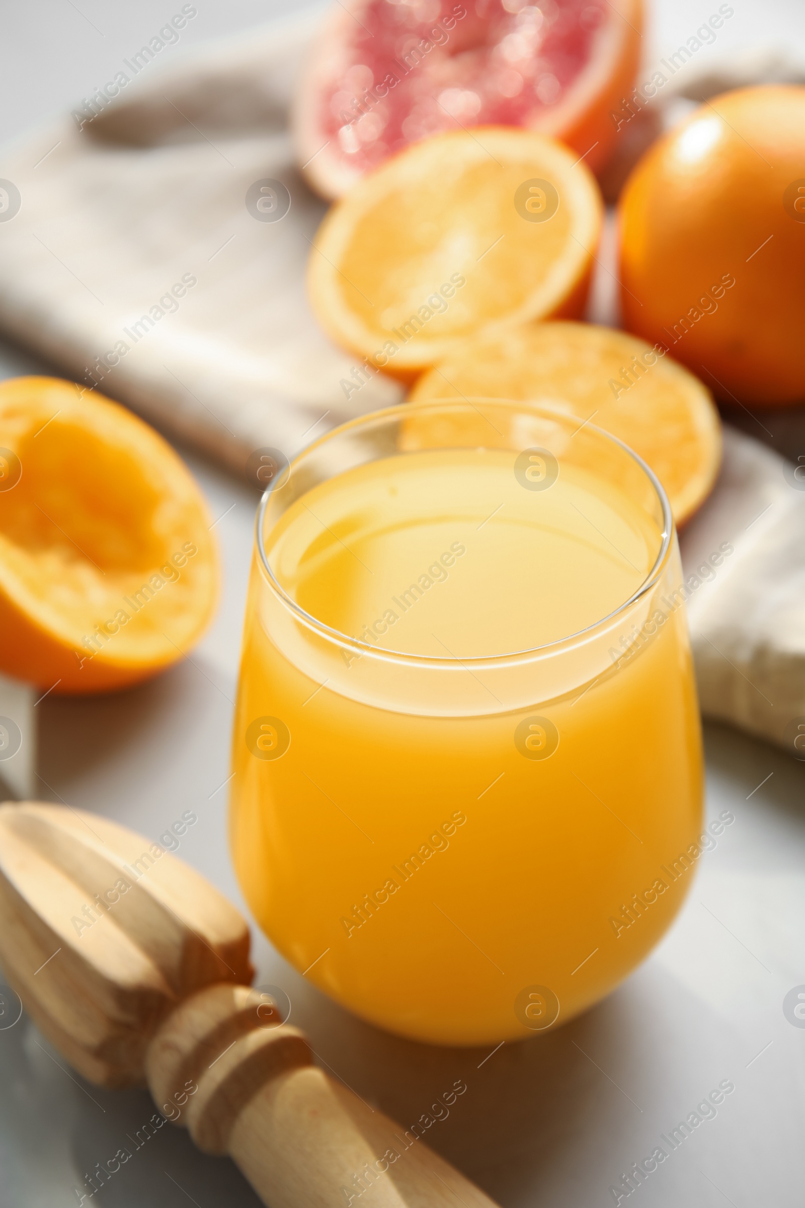 Photo of Freshly made juice, oranges and reamer on light grey table